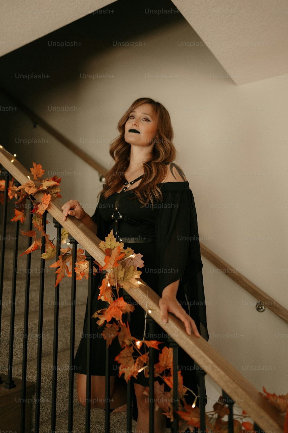 a woman in a black dress standing on a stair case
