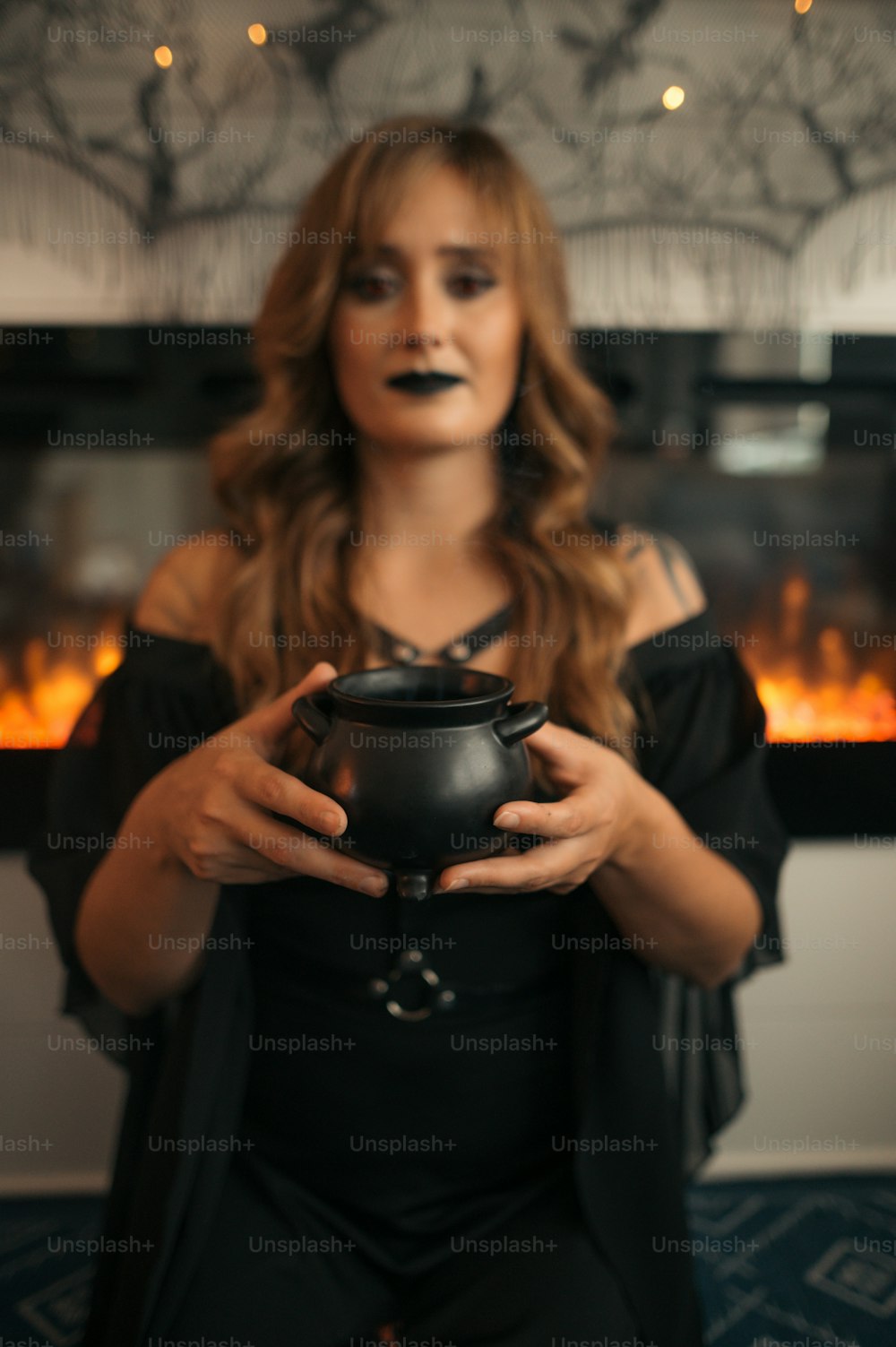a woman holding a caulder in front of a fireplace