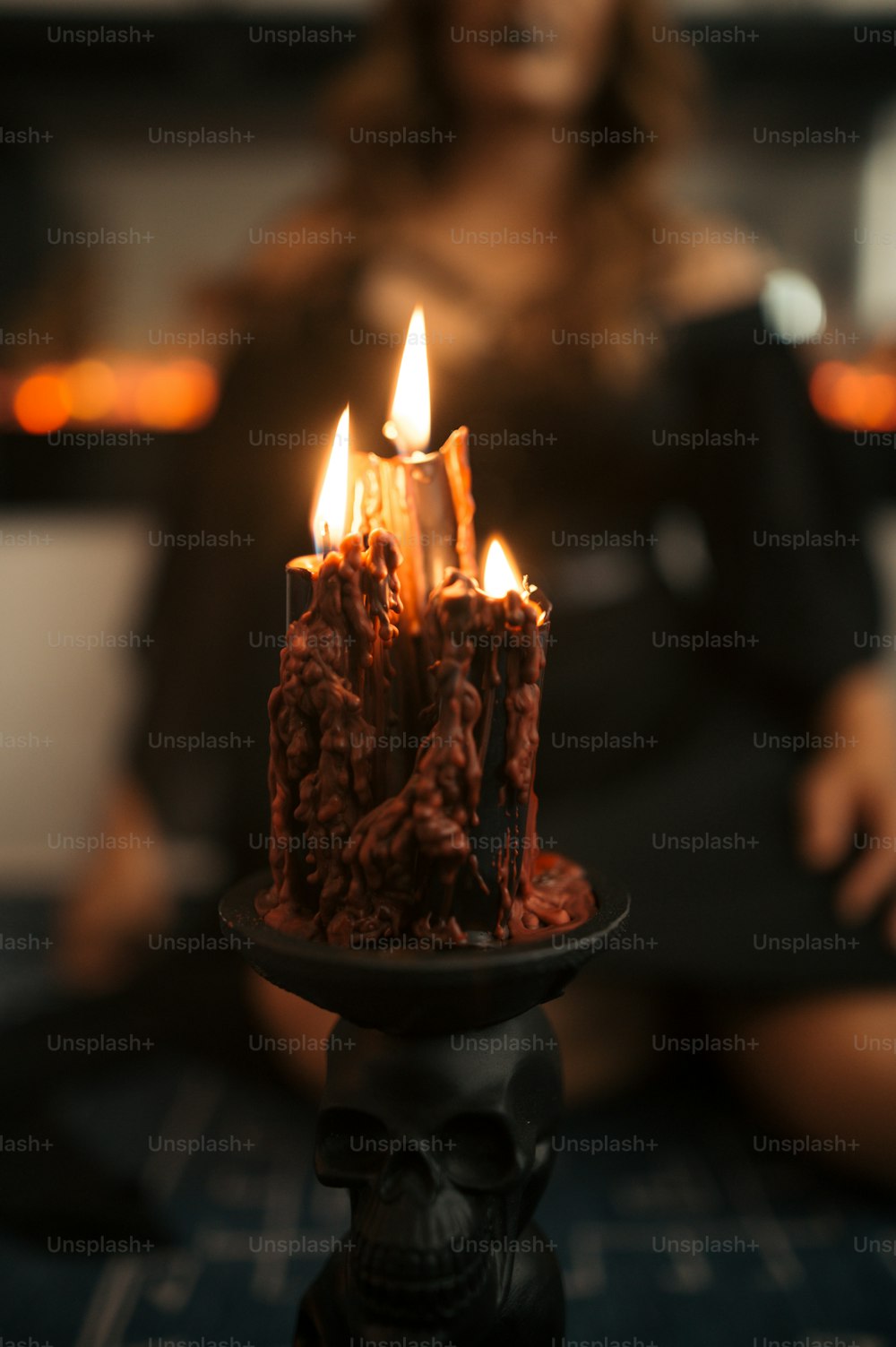 a woman sitting in front of a cake with lit candles