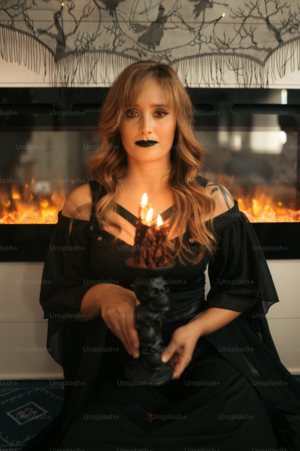 uma mulher em um vestido preto segurando uma vela acesa