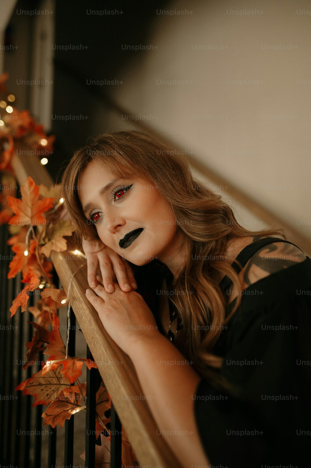 a woman with red eyes and black makeup leaning on a railing