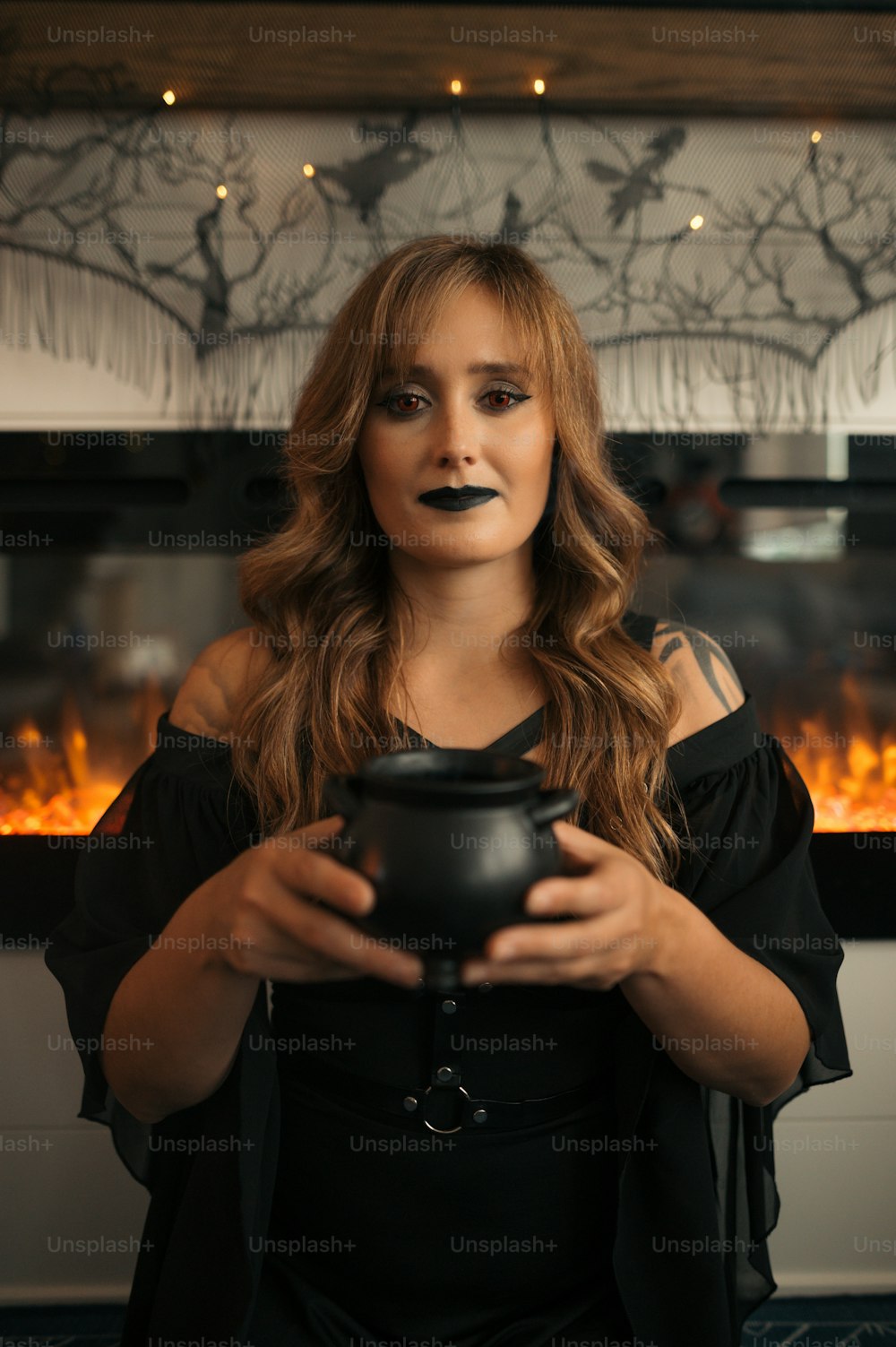 a woman in a black dress holding a black pot