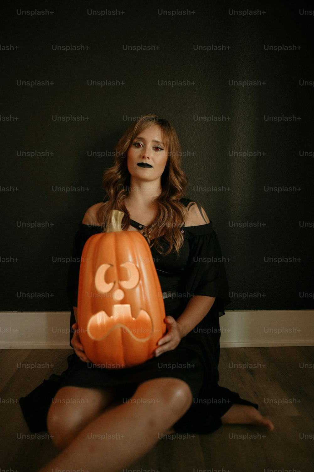 a woman sitting on the floor holding a carved pumpkin