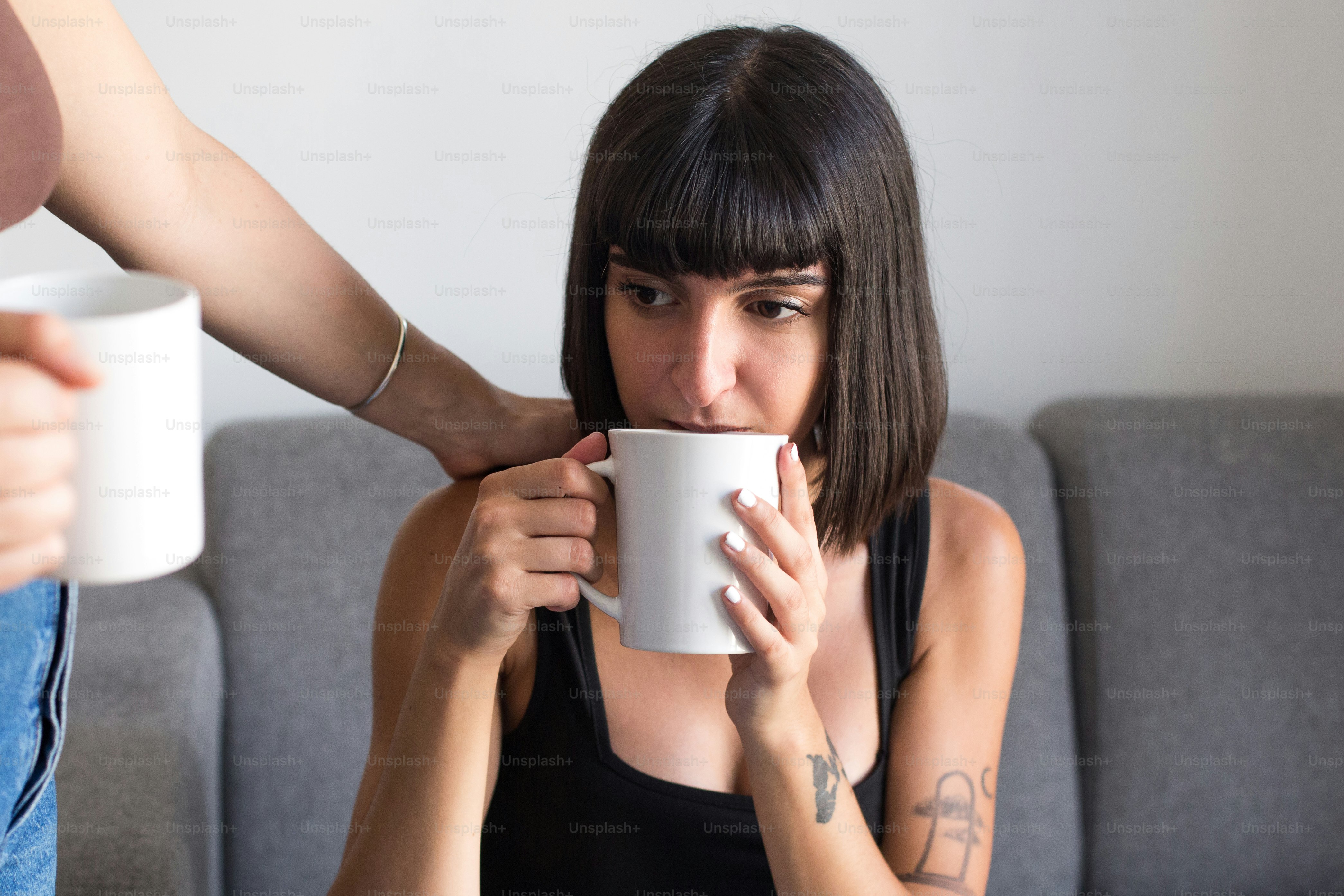 a woman sitting on a couch holding a coffee cup