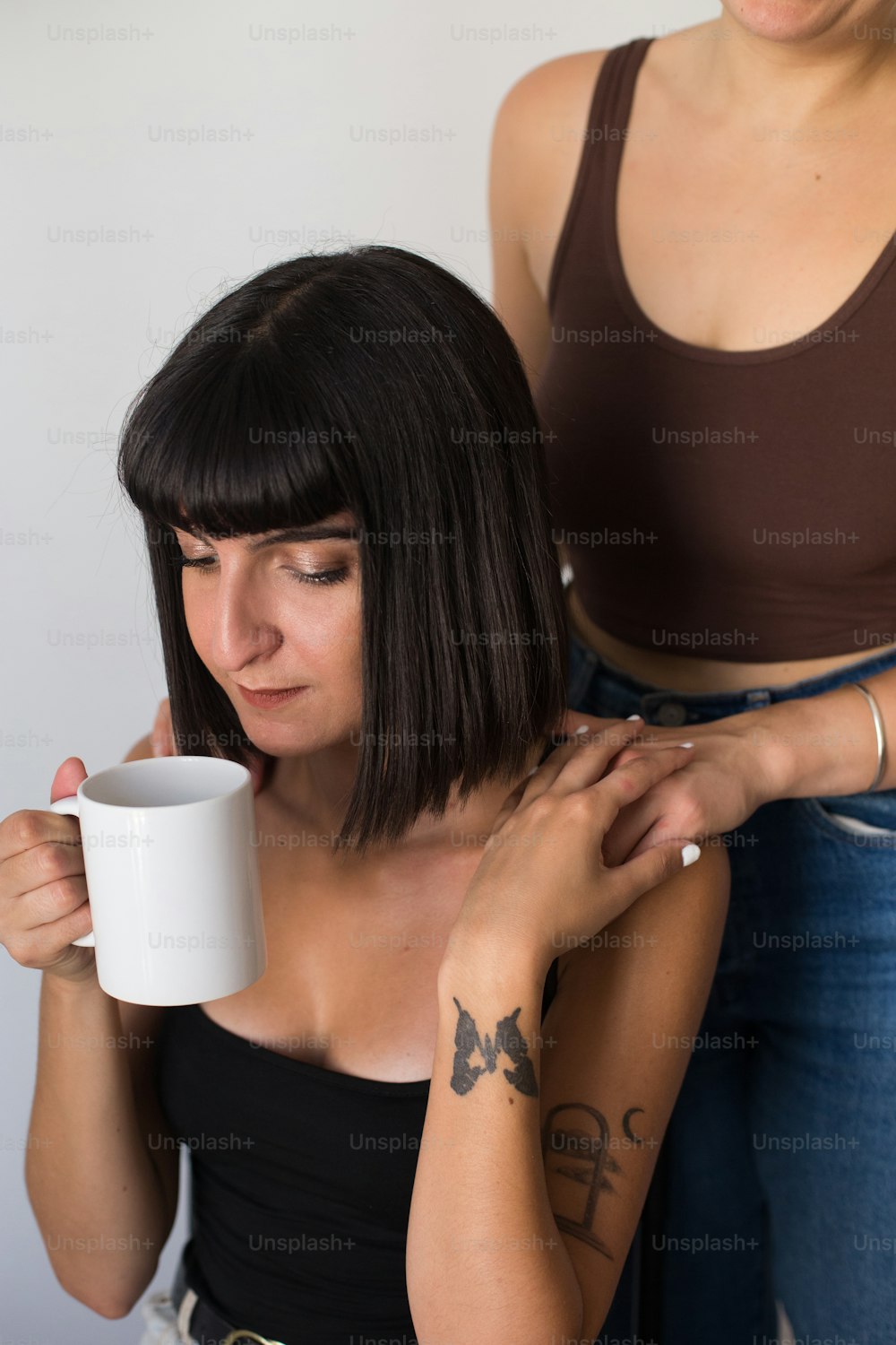a woman holding a coffee mug while another woman looks on