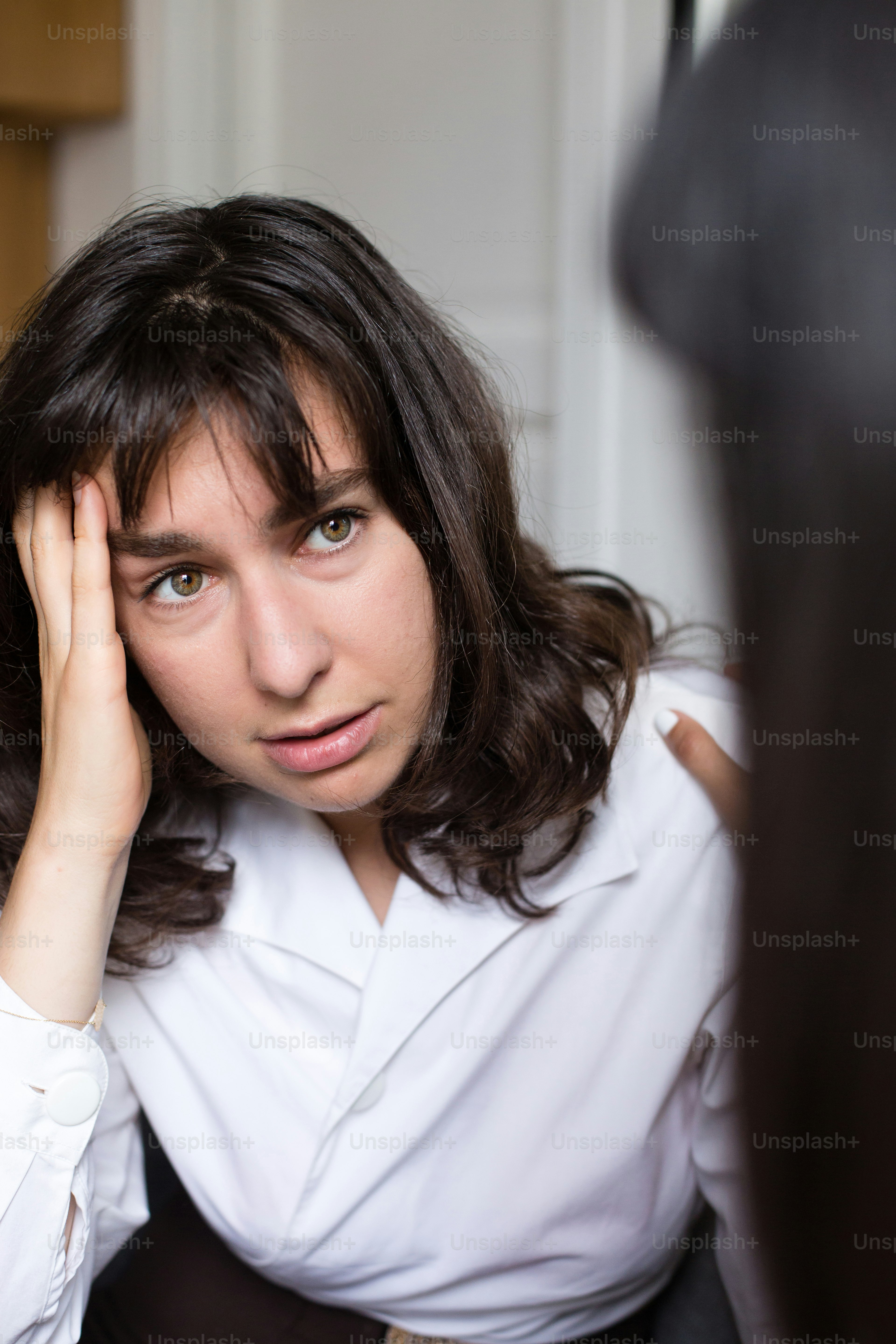 a woman sitting in a chair with her hand on her head