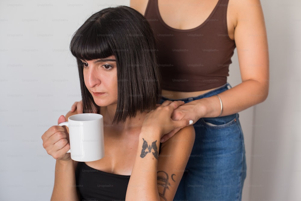 Una mujer arreglándose el pelo por una mujer con una taza