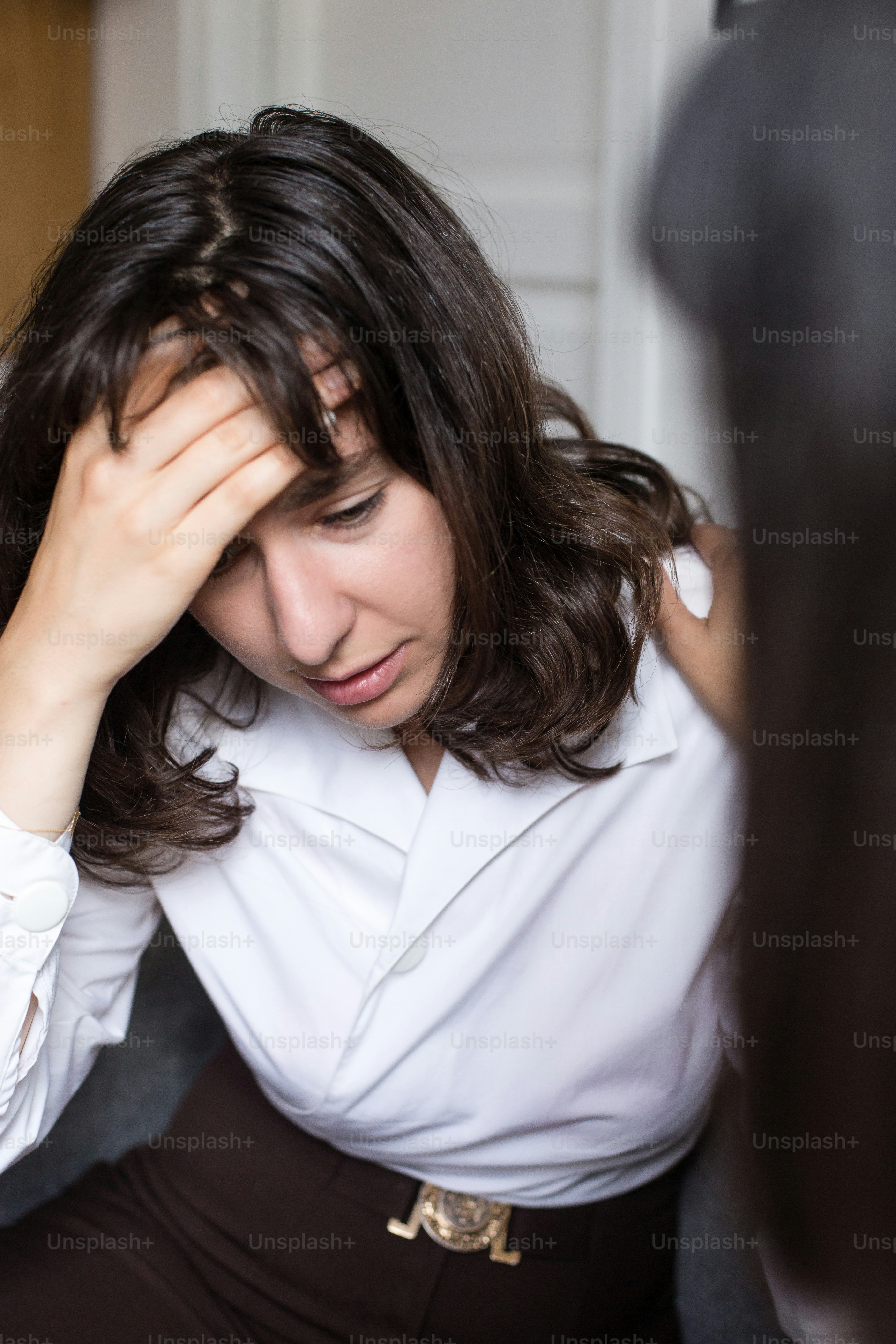 Eine Frau, die auf einer Couch sitzt und ihren Kopf hält