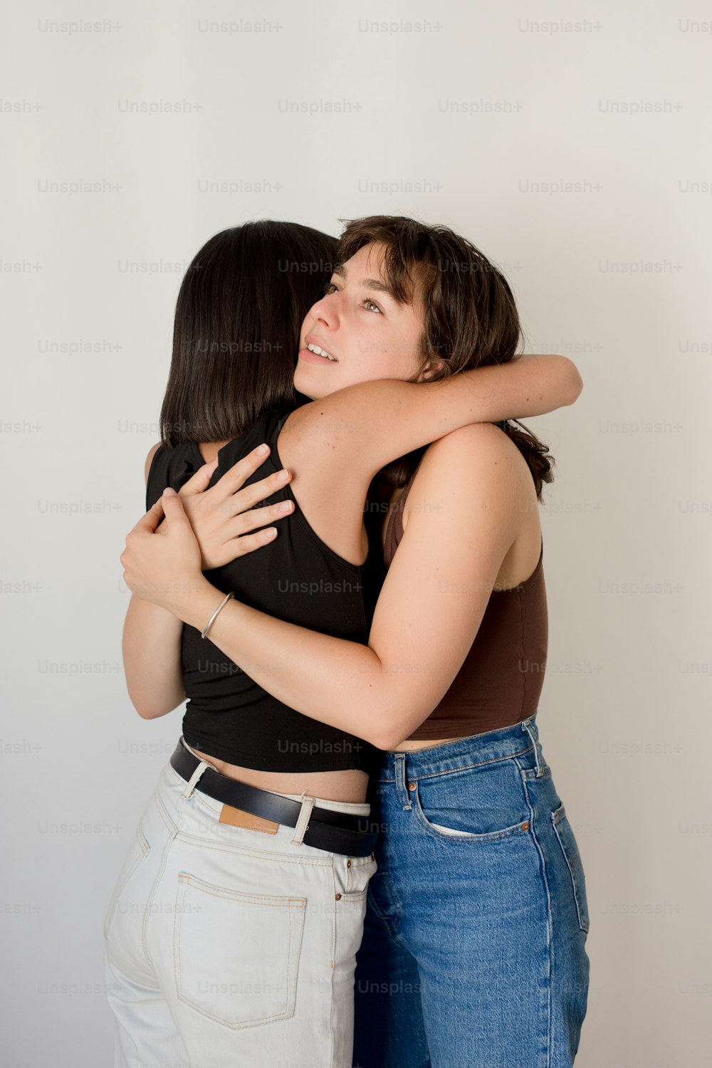 two women hugging each other in a white room