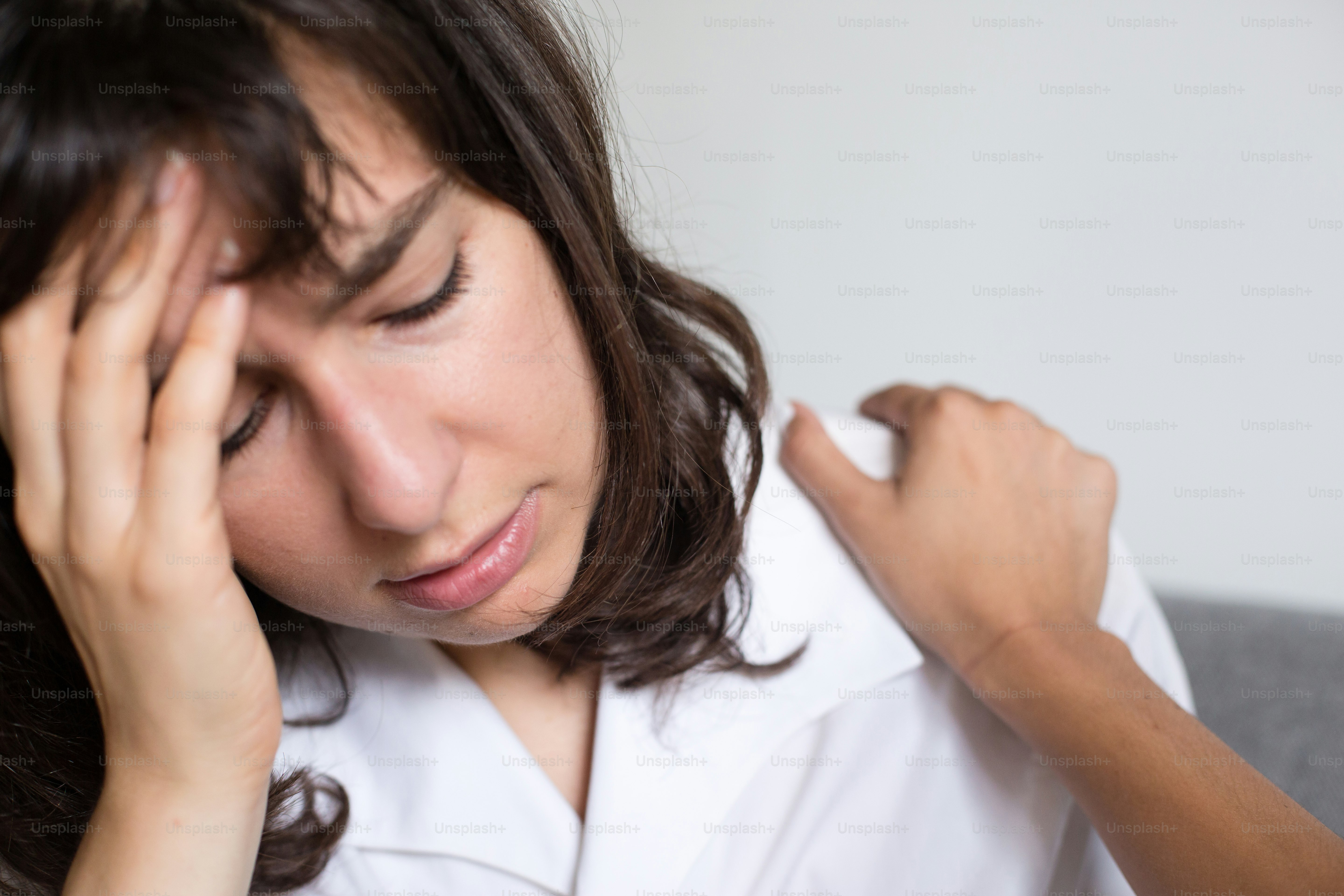 a woman in a white shirt is holding her head