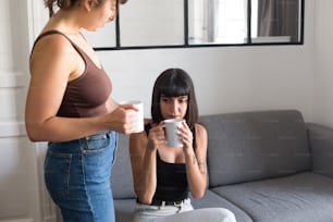 uma mulher sentada em um sofá segurando uma xícara de café