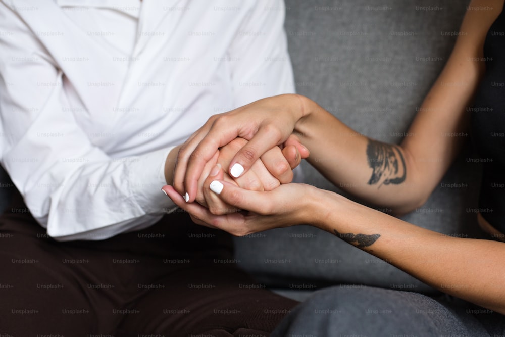 a man and woman holding hands while sitting on a couch