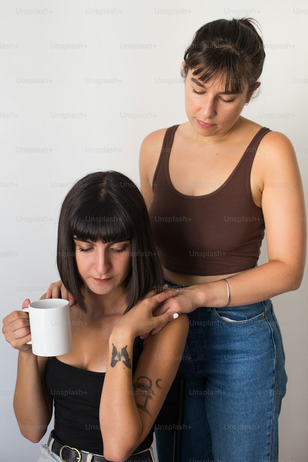 eine Frau, die eine Kaffeetasse neben einer anderen Frau hält