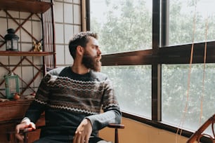 a man sitting in a chair looking out a window