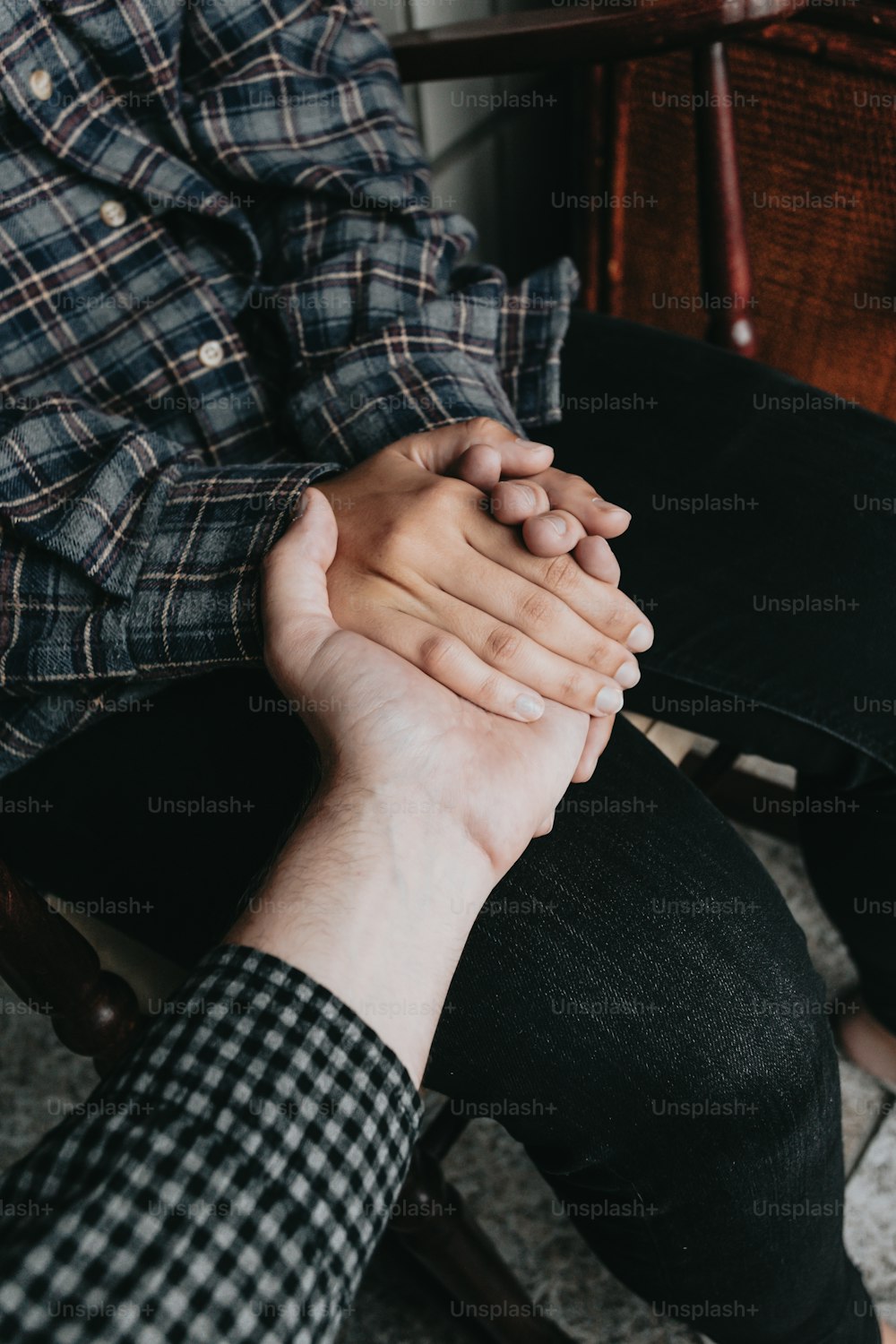 two people holding hands while sitting on a chair