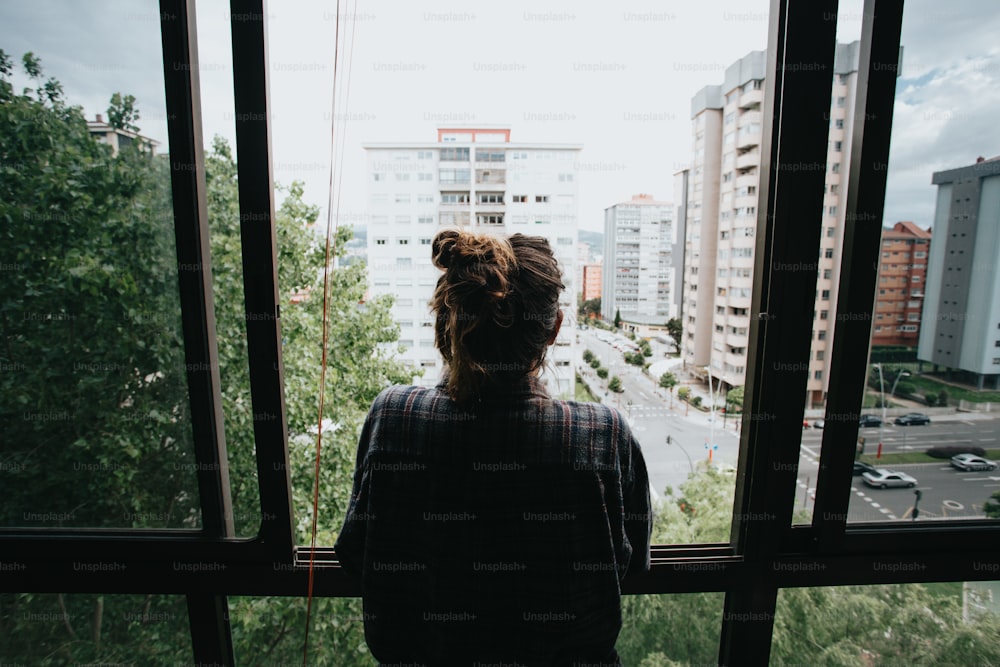 une personne regardant par une fenêtre sur une ville