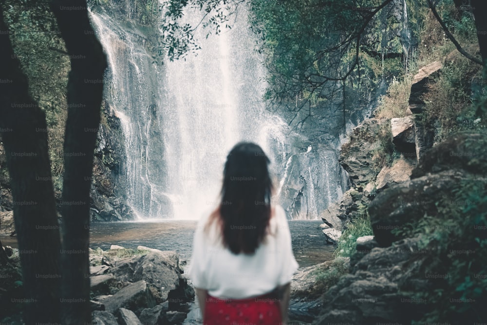 uma mulher em pé em frente a uma cachoeira