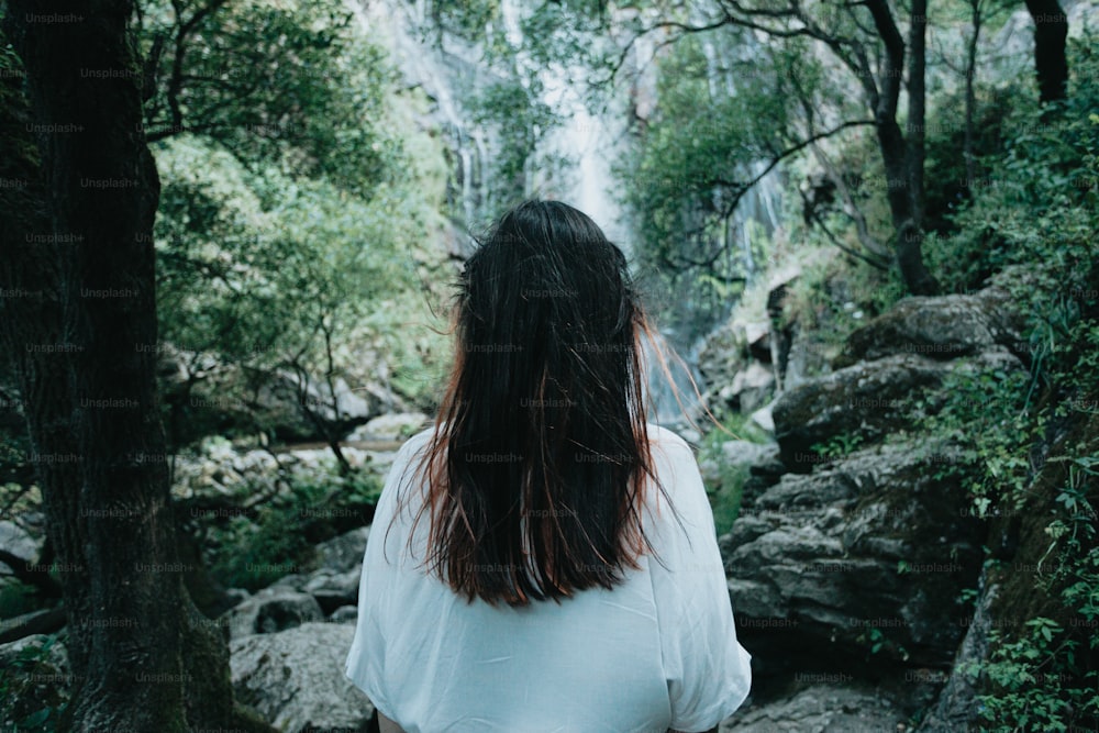 uma mulher em pé em frente a uma cachoeira