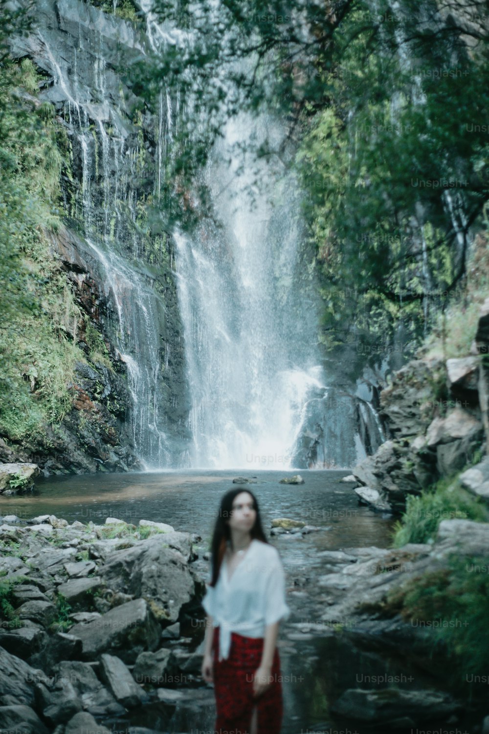 a woman standing in front of a waterfall