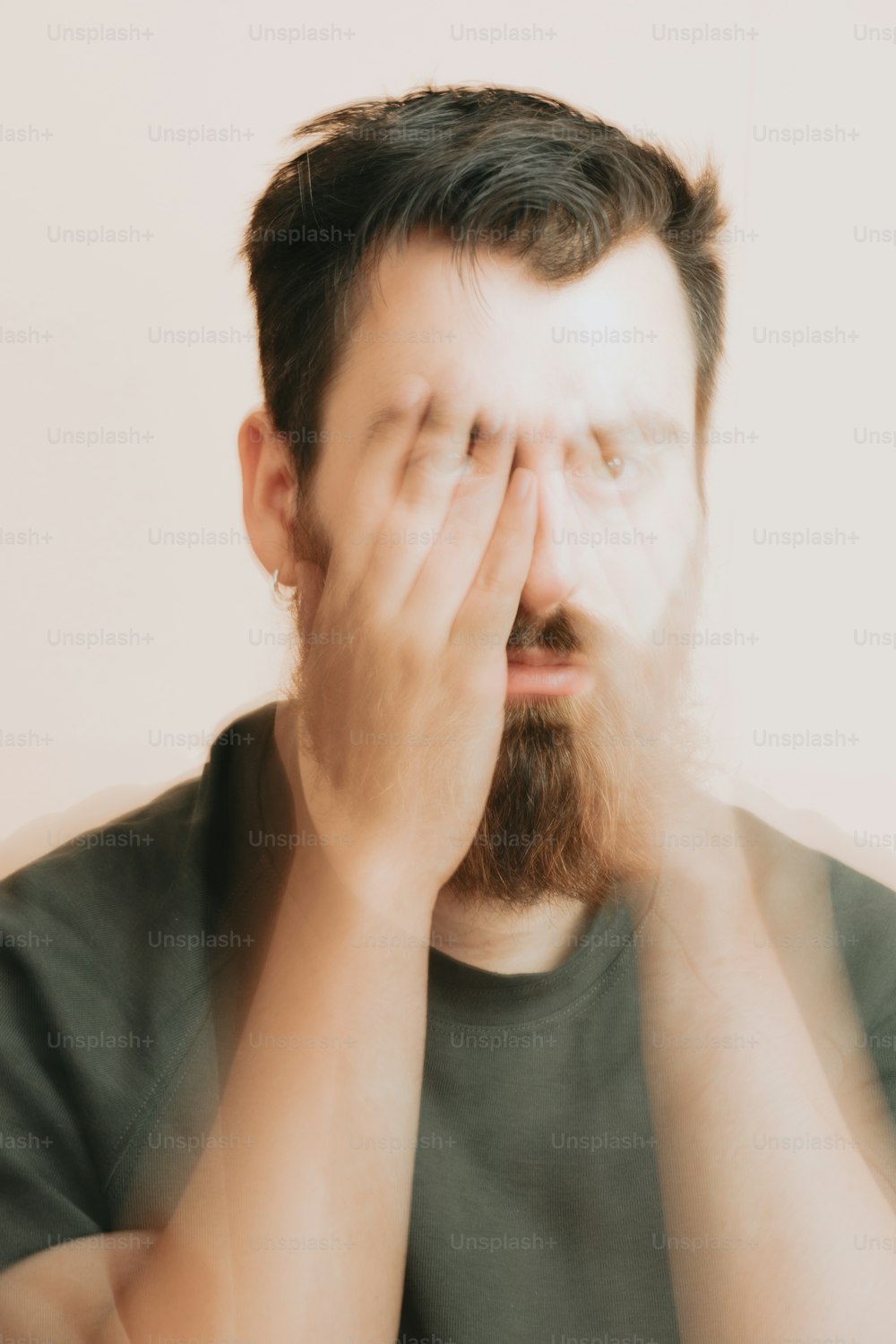um homem com barba cobrindo os olhos
