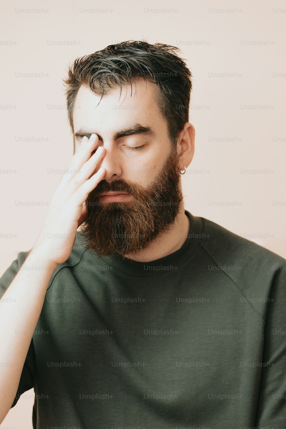 Un homme avec une barbe tient sa main contre son visage