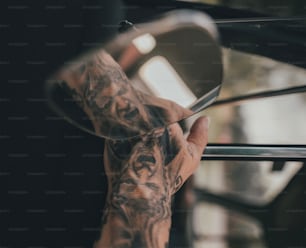 a man's hand holding a pair of scissors in front of a mirror