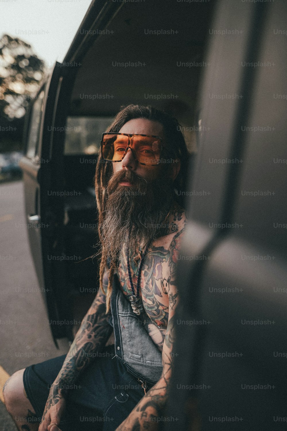 a man with long hair and tattoos sitting in the back of a truck
