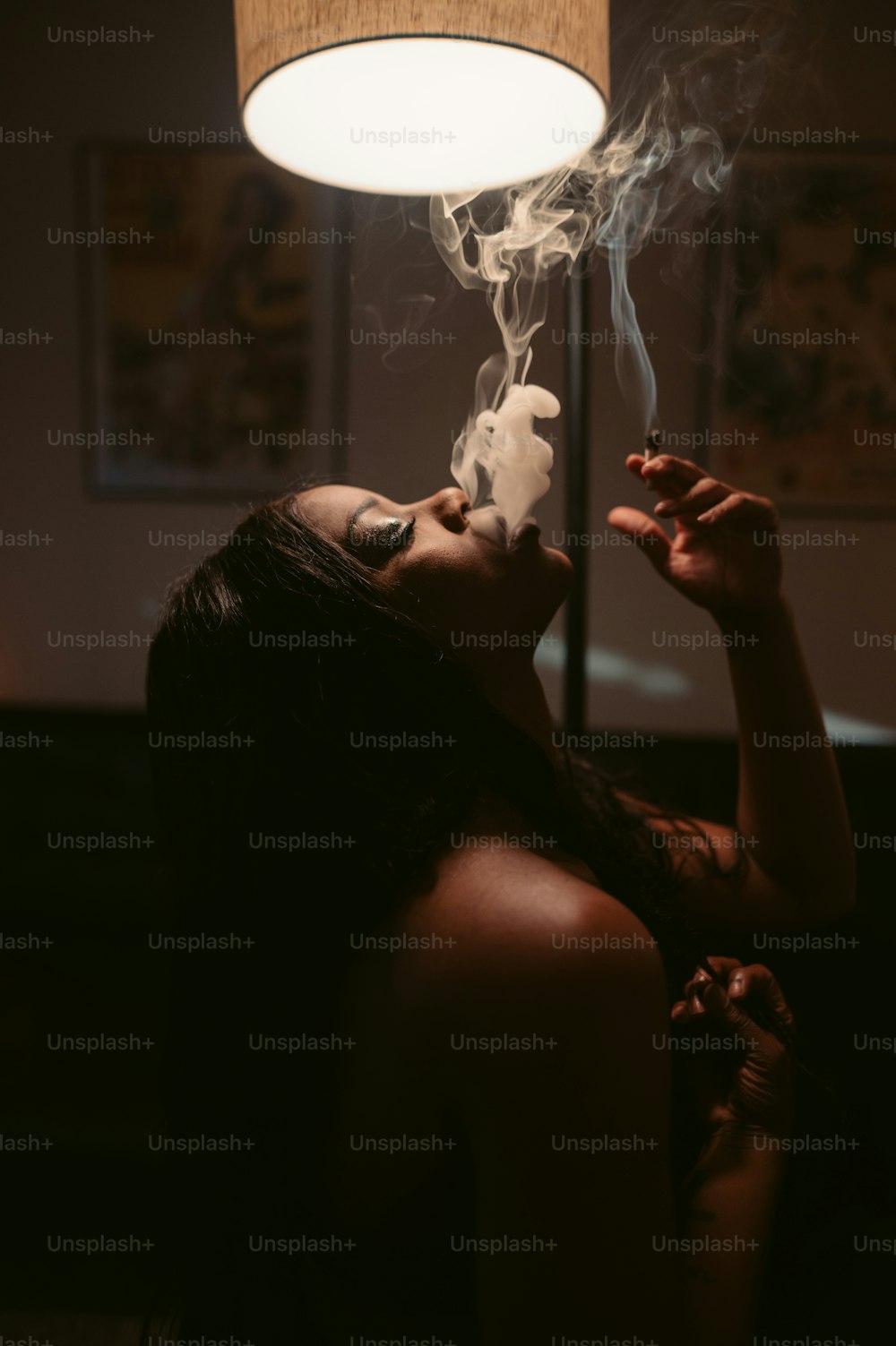 uma mulher fumando um cigarro em um quarto escuro