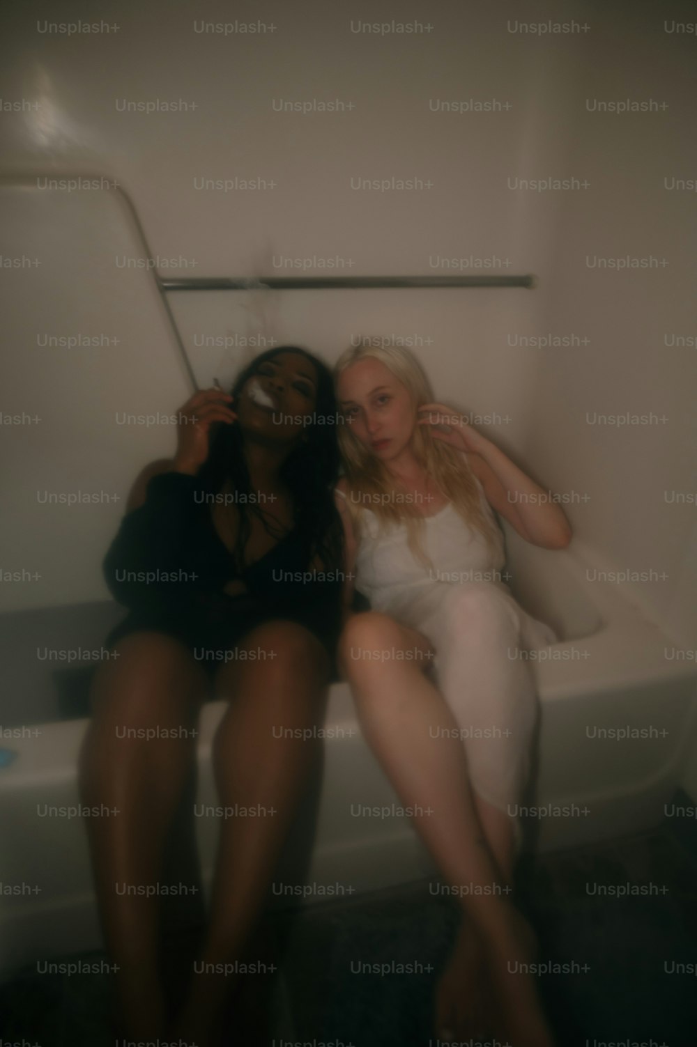 two women sitting on a bathtub in a bathroom