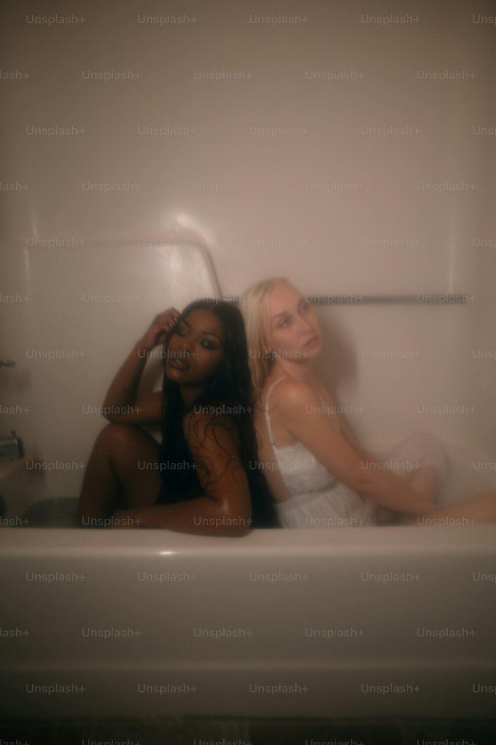 two women sitting in a bathtub in a bathroom
