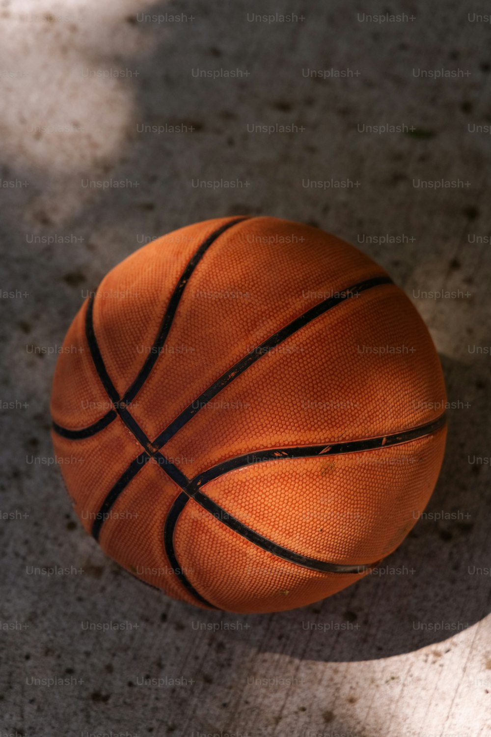 Una pelota de baloncesto sentada en el suelo a la sombra