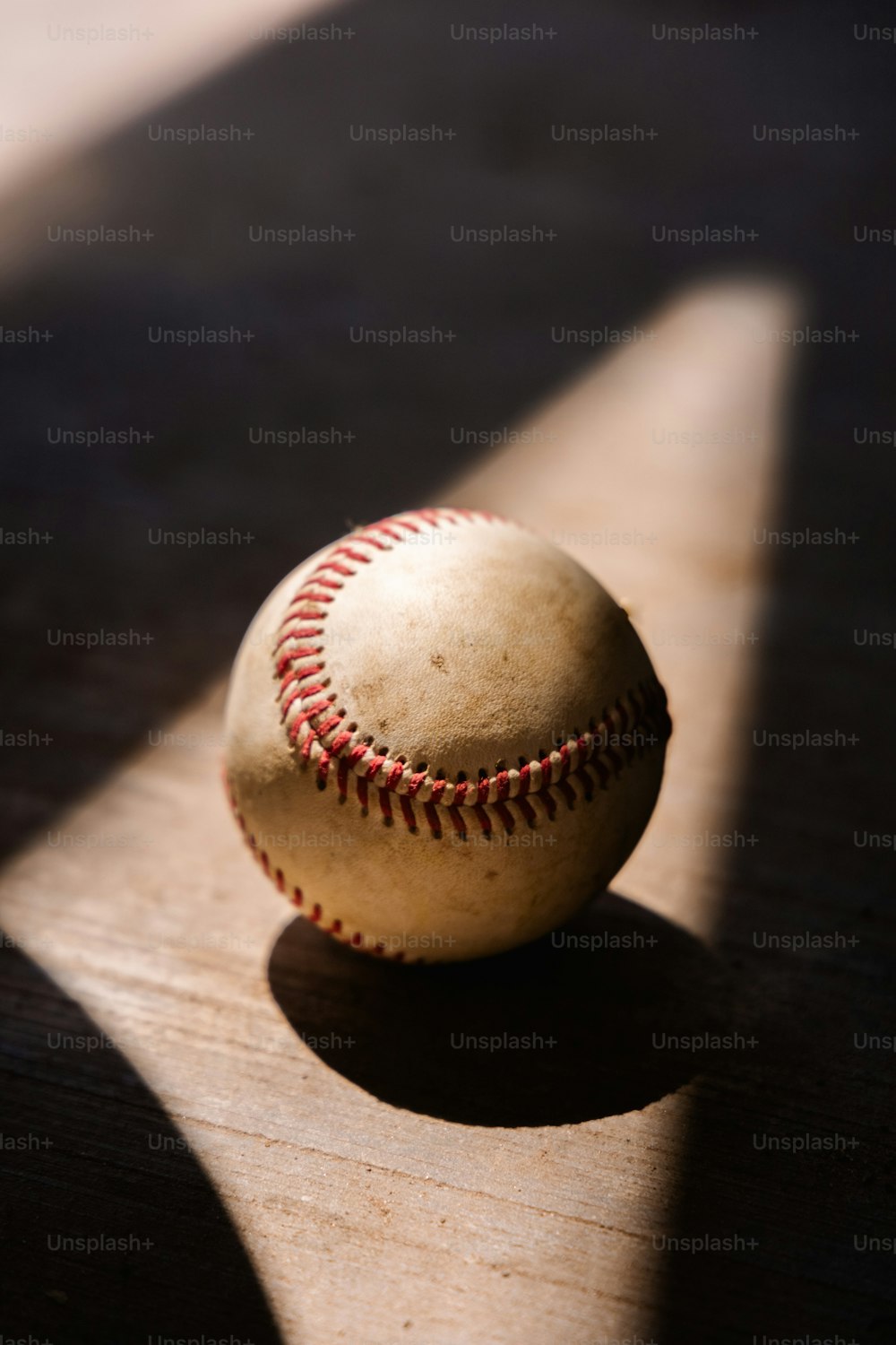 Una pelota de béisbol sentada encima de una mesa de madera