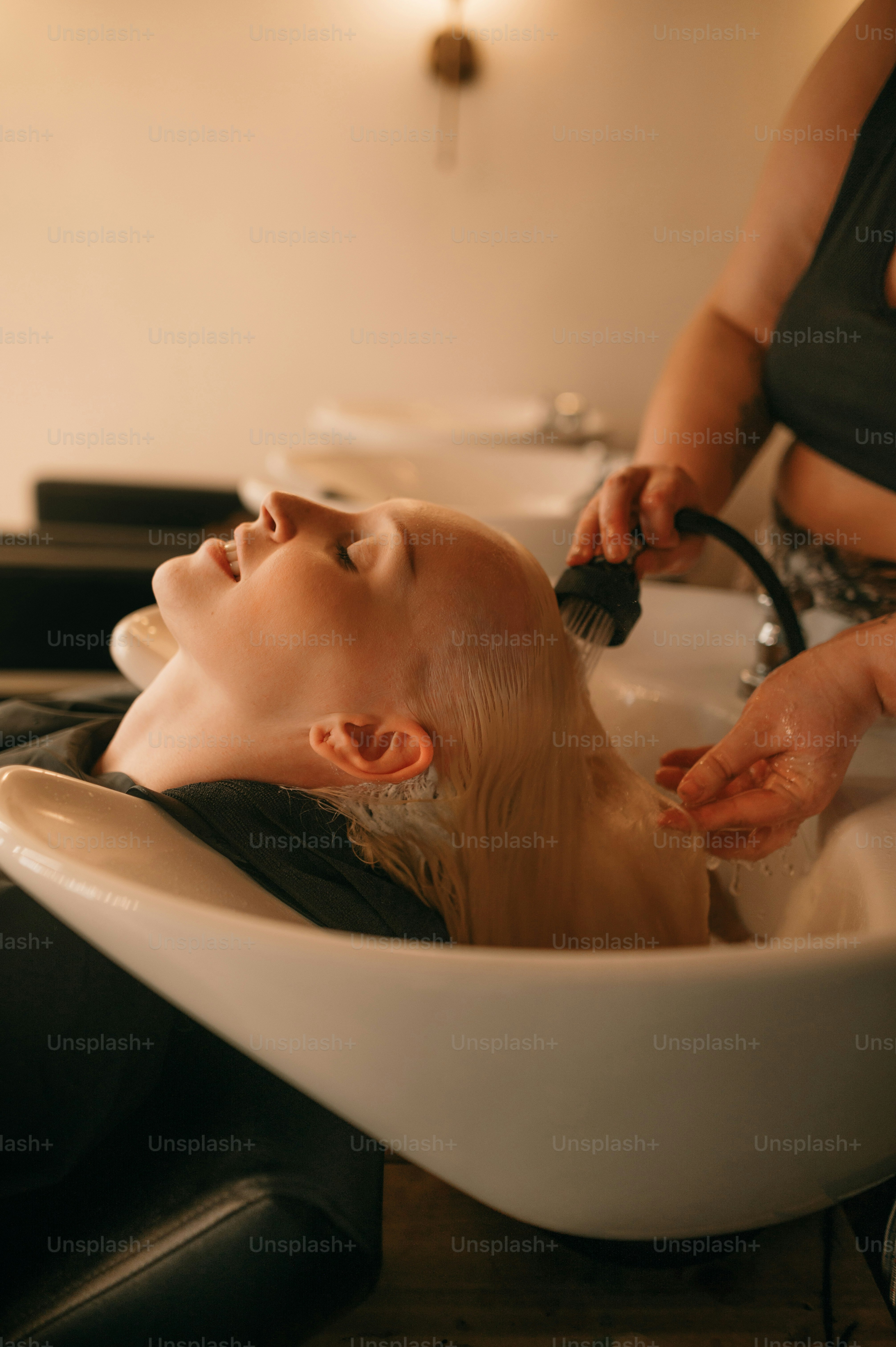 Eine Frau, die sich in einem Salon die Haare waschen lässt