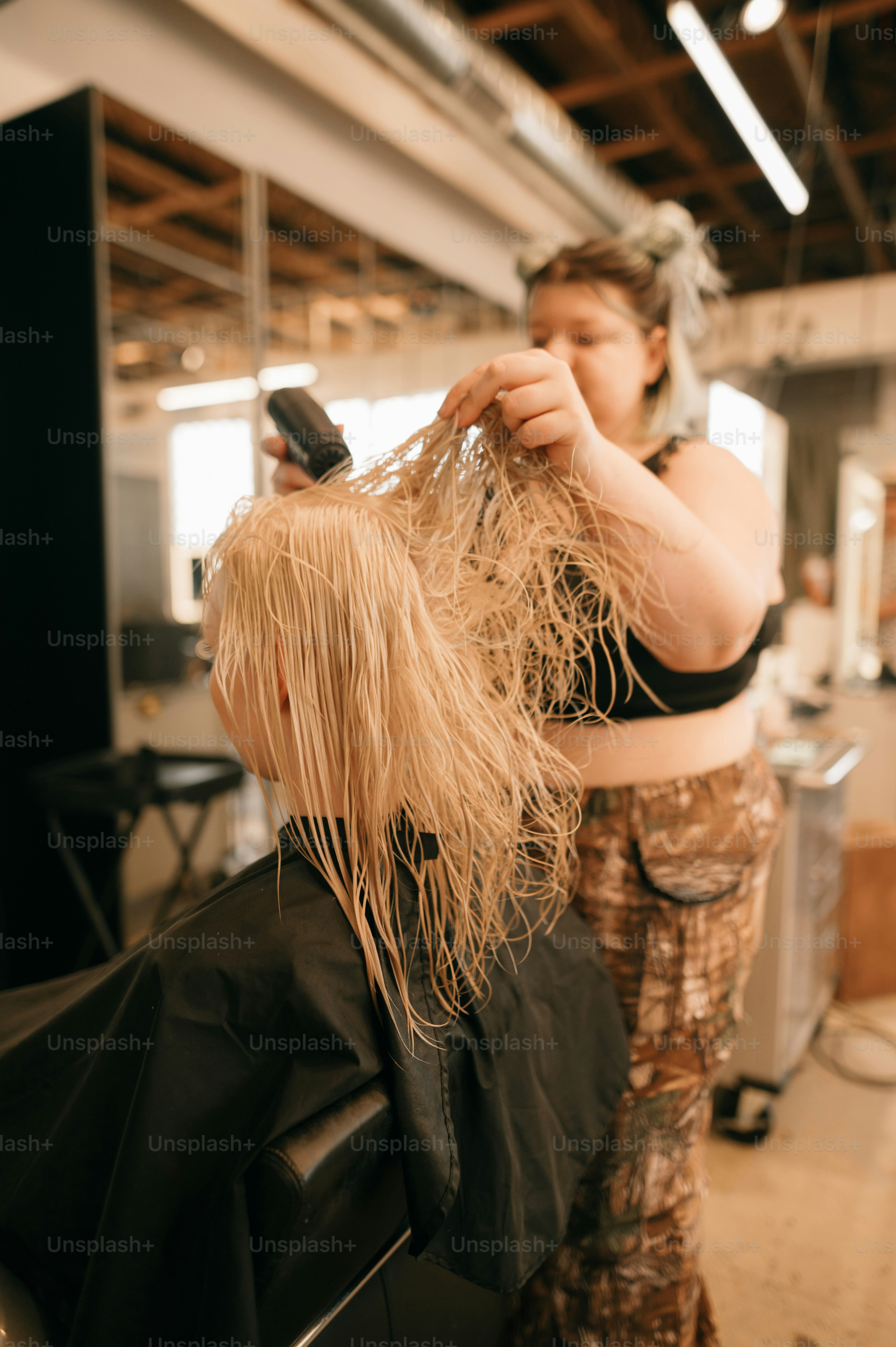 a woman cutting another woman's hair with a hair dryer