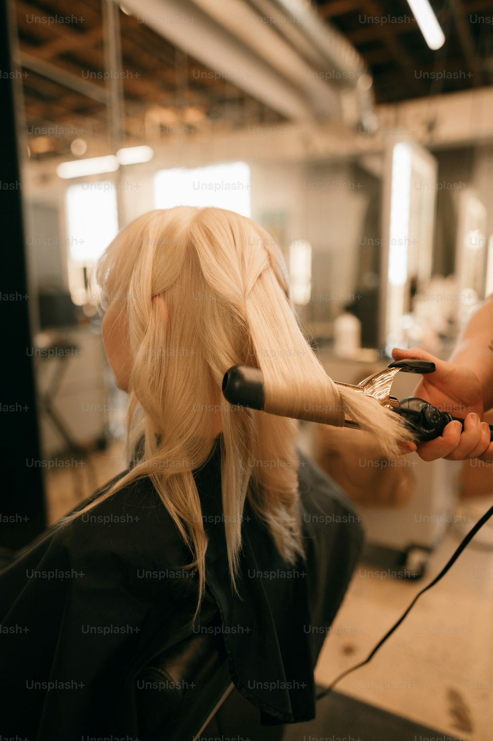 a woman is blow drying her blonde hair