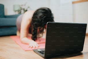 a woman laying on a yoga mat in front of a laptop