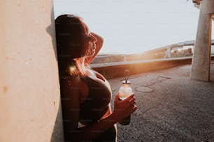 a woman standing next to a wall holding a bottle