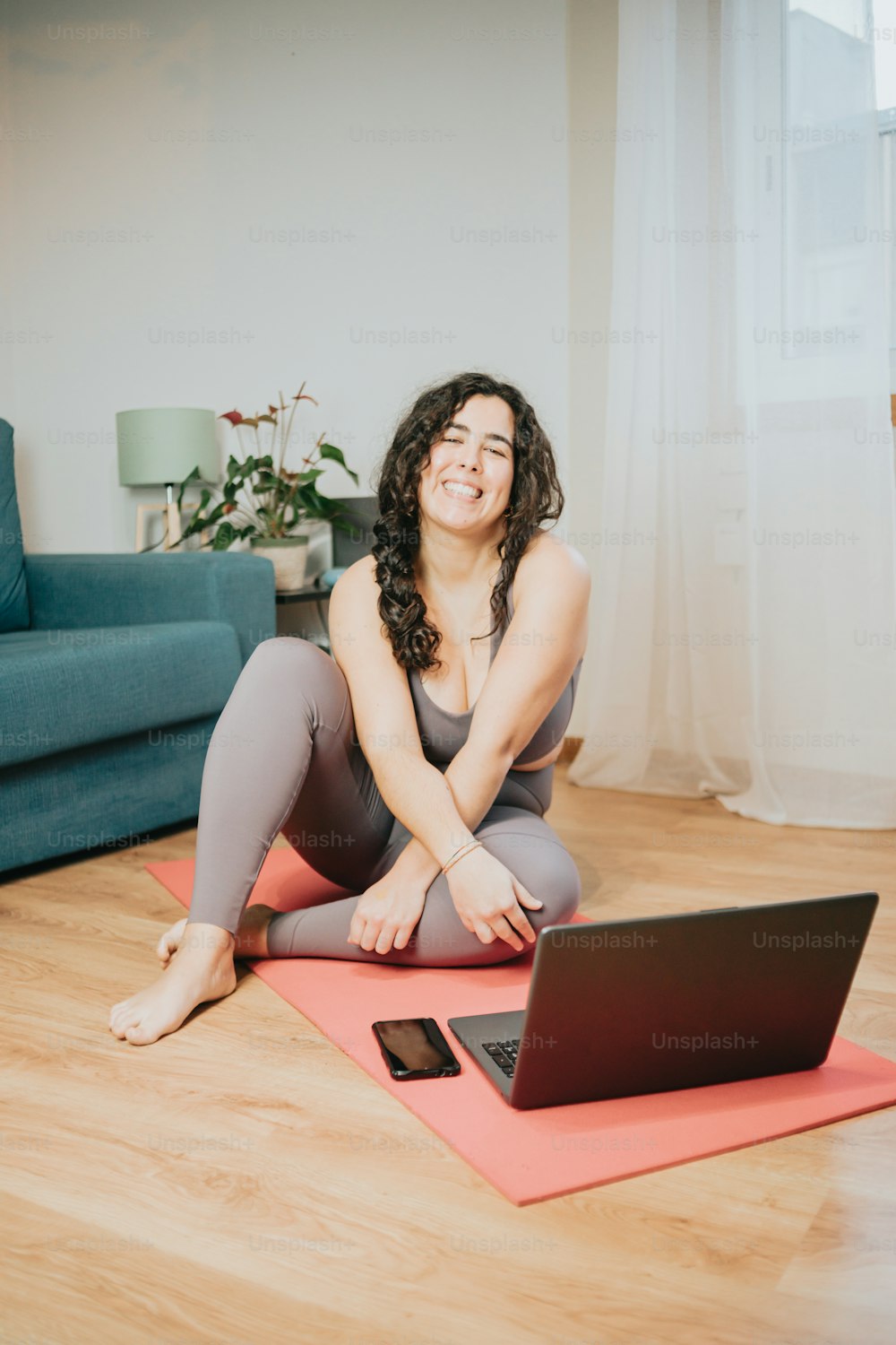a woman sitting on a yoga mat with a laptop