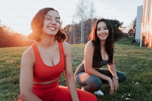 two women sitting on the ground in the grass