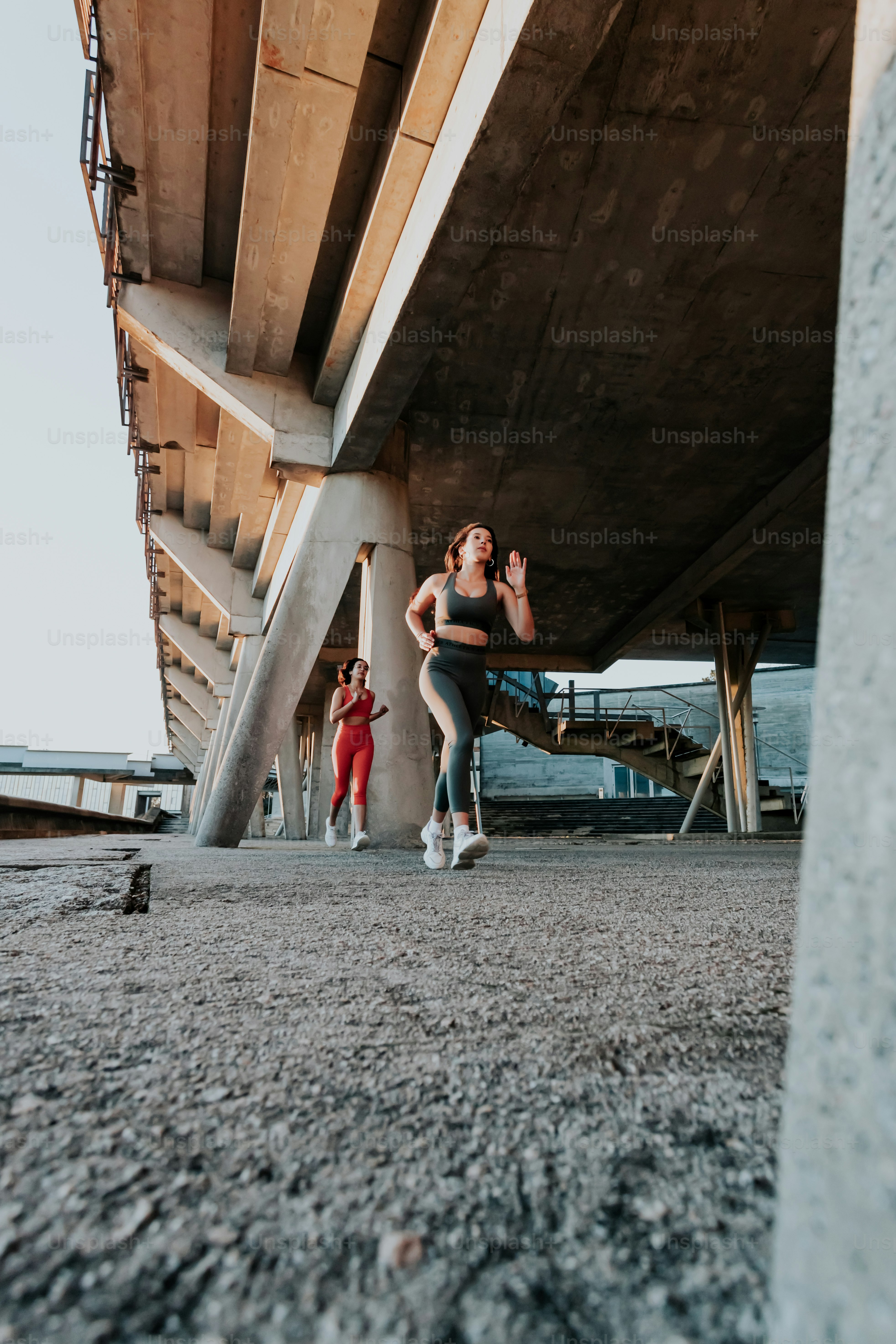 Eine Frau rennt mit einer anderen Frau unter einer Brücke