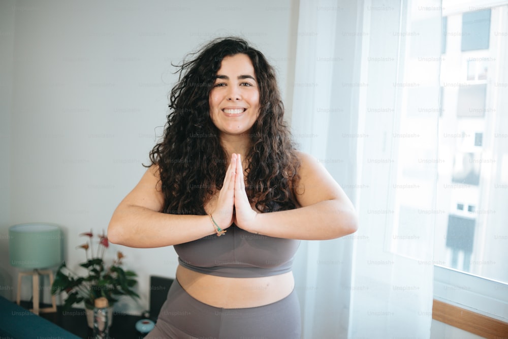 a woman standing in a yoga pose with her hands together