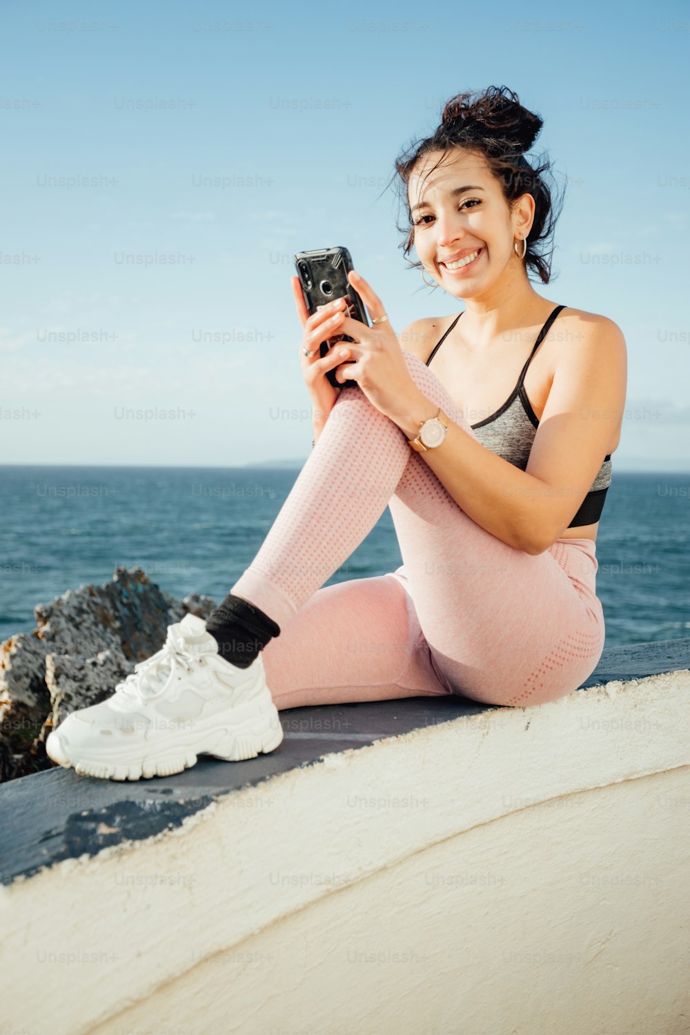 Una mujer sentada en una repisa con un teléfono celular