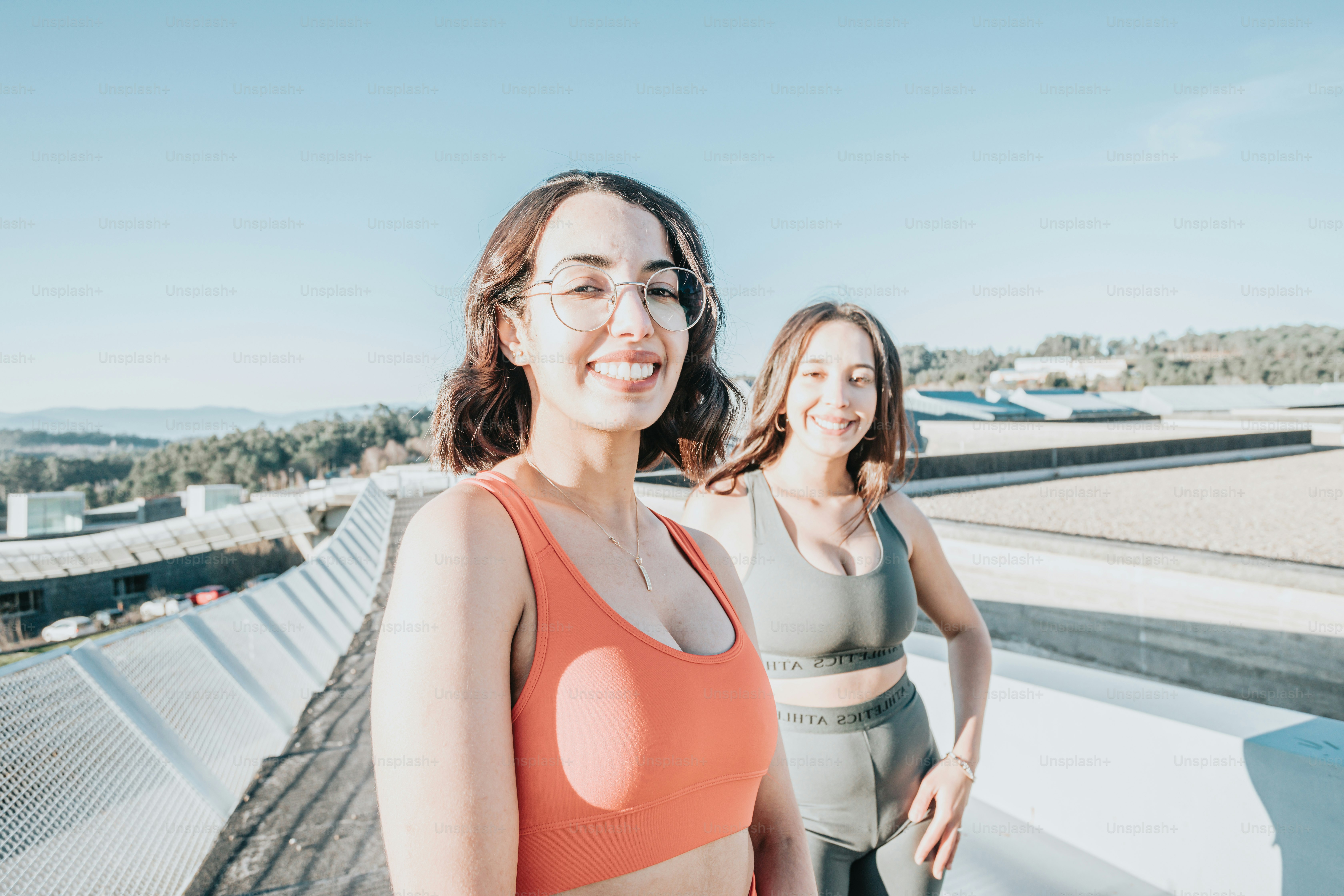 two women in sports bras standing on a roof