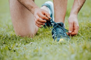 a person tying a shoelace on a grass field