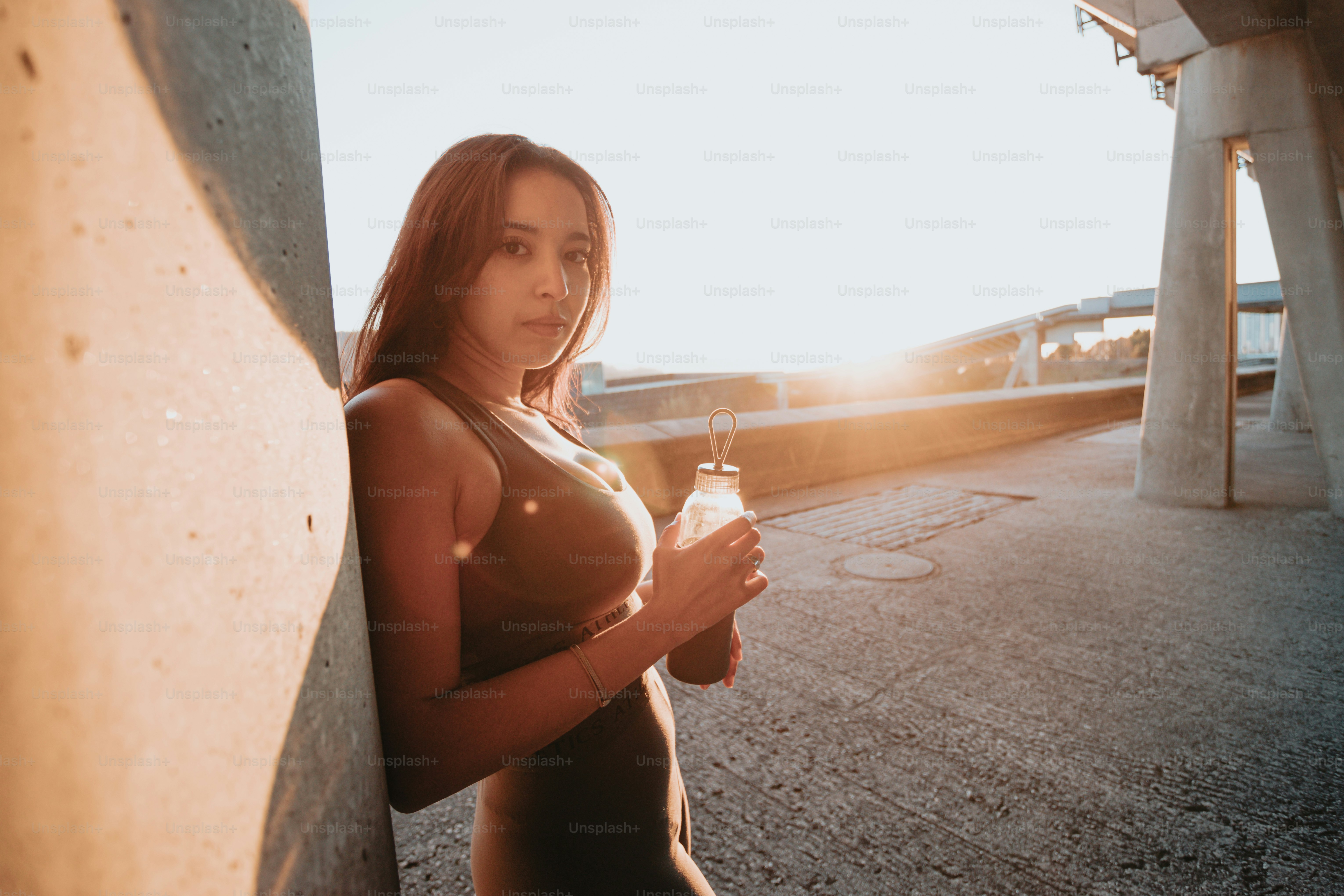 a woman standing next to a wall holding a bottle