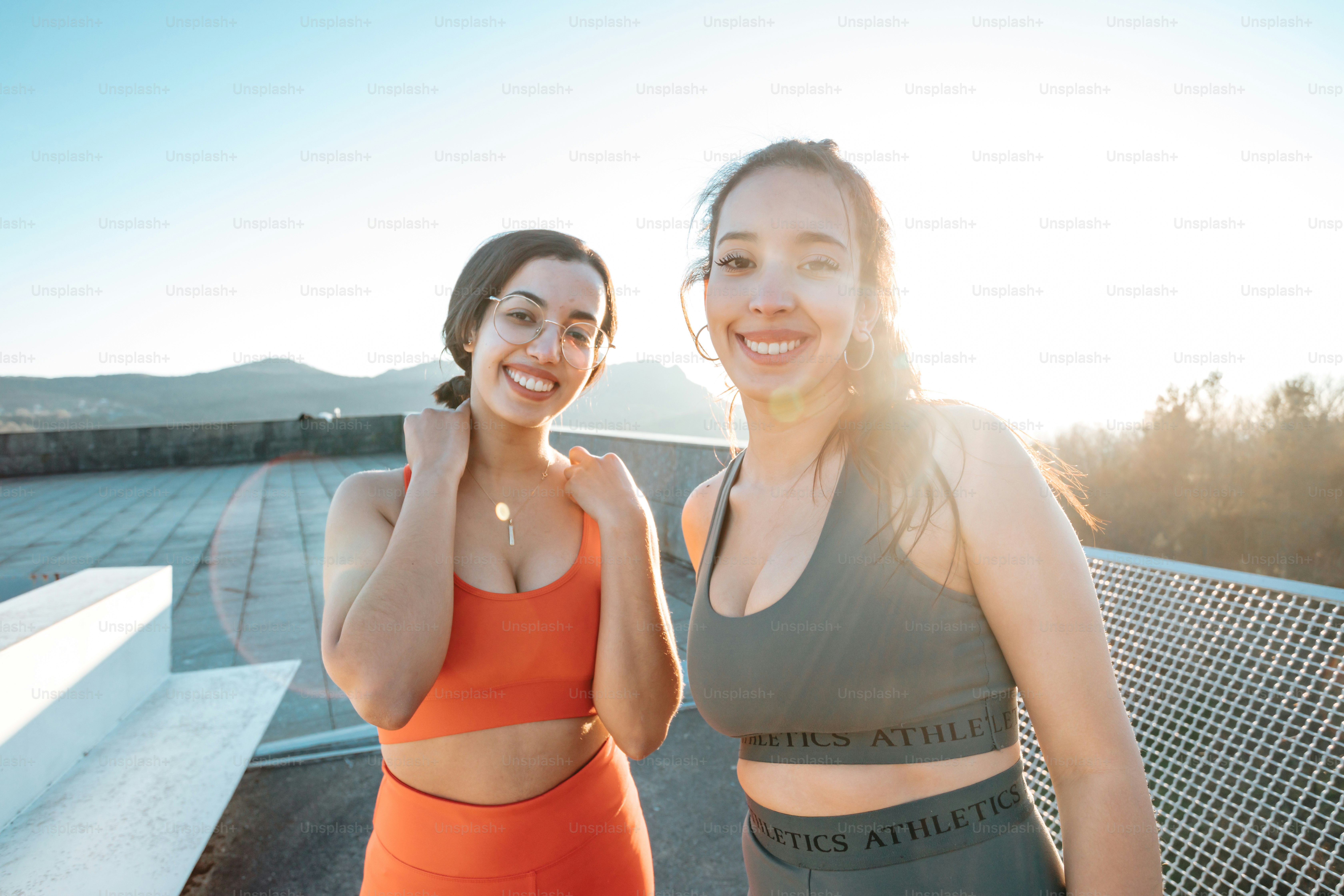 duas mulheres em pé uma ao lado da outra em frente a uma cerca
