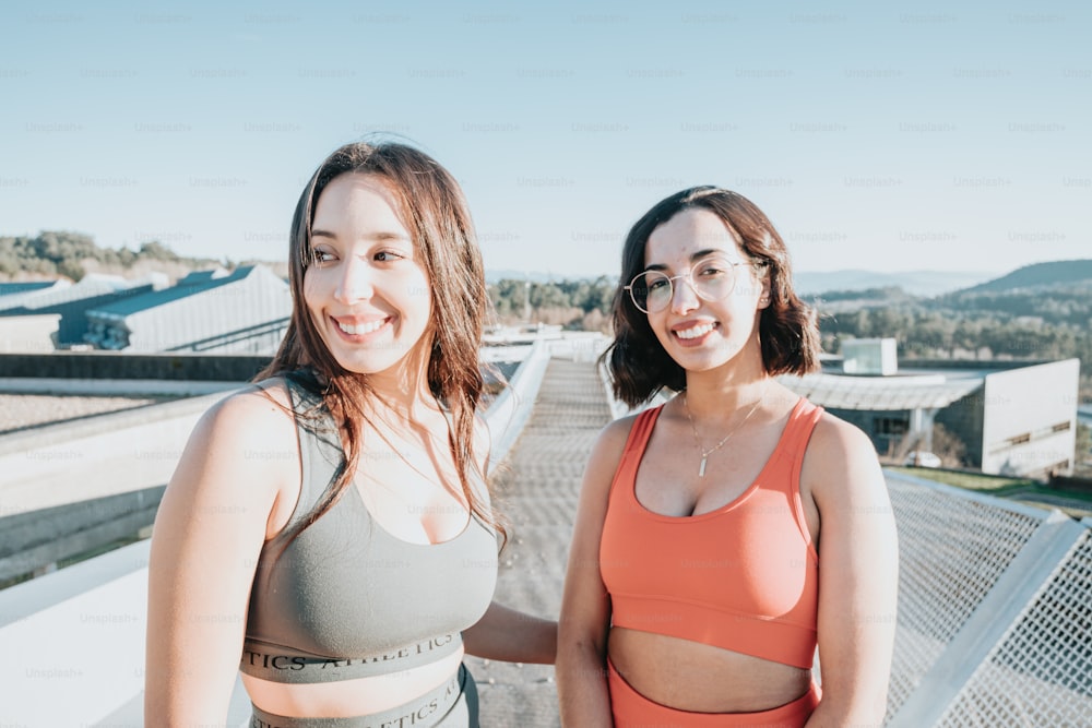 two women standing next to each other on a roof