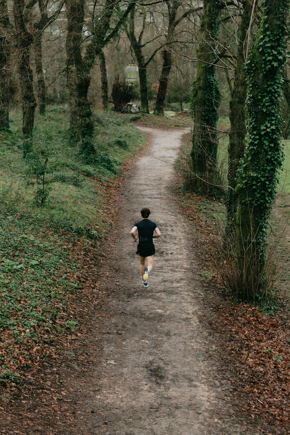 a person running down a dirt road in the woods