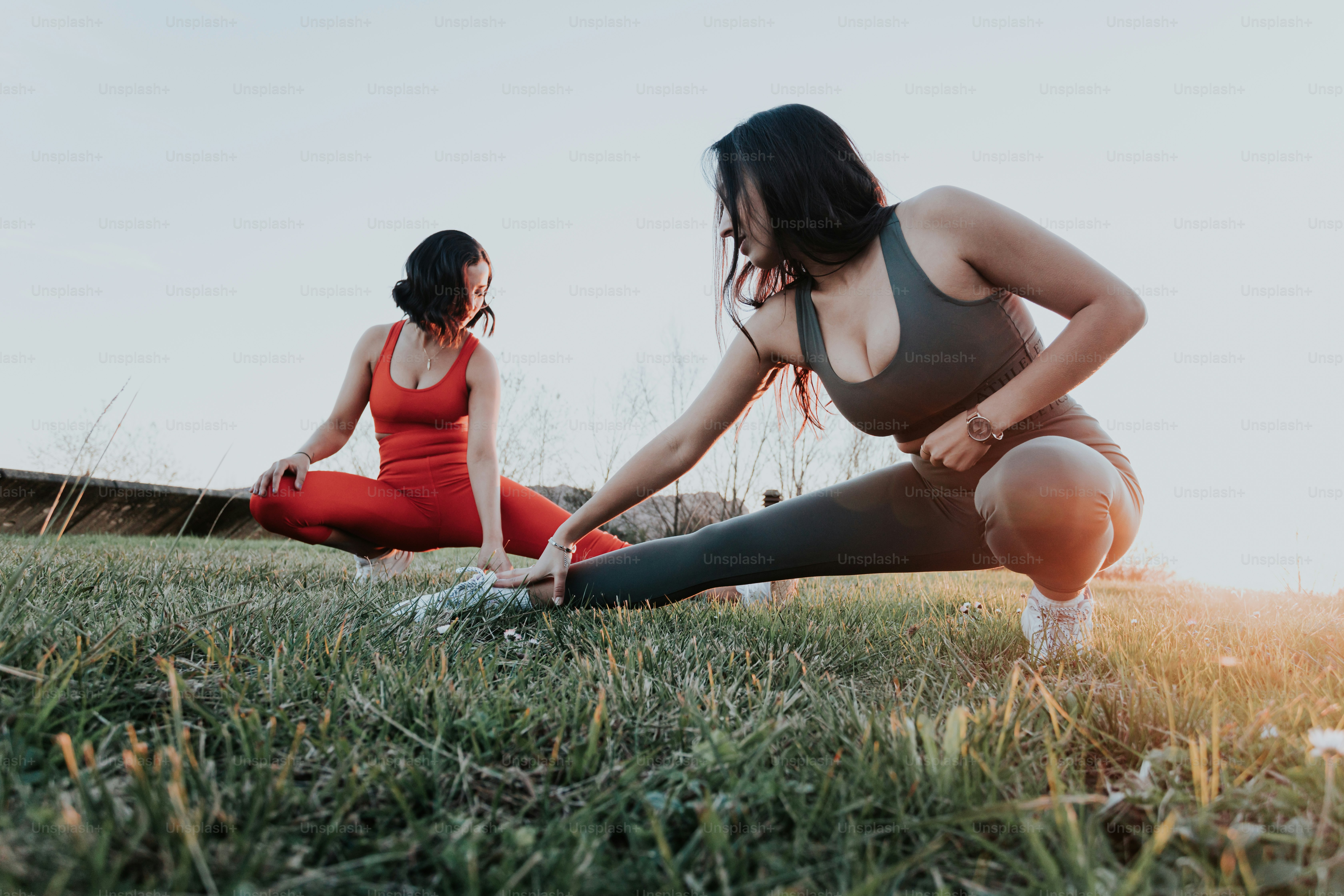 a couple of women sitting on top of a lush green field