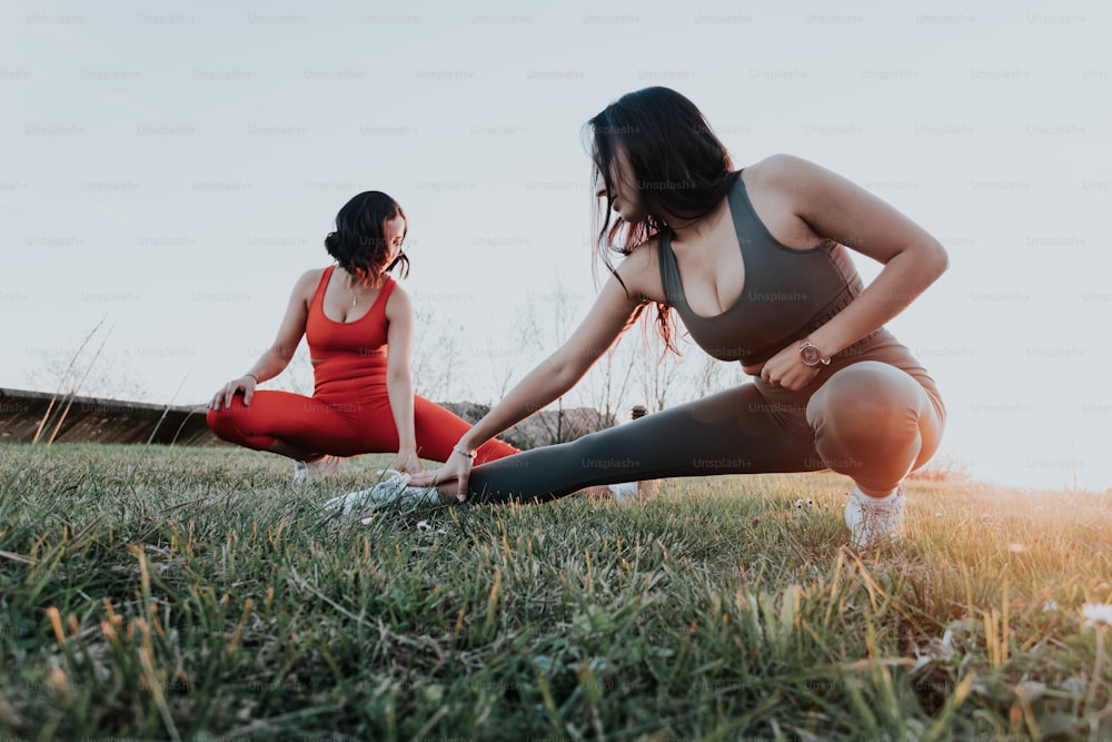 a couple of women sitting on top of a lush green field